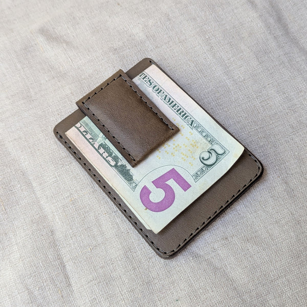 Brown leather money clip holding a $5 bill on a light gray fabric background

woolly made unisex men's cardholder money clip magnet leather wallet shop boston gift store sowa boutique