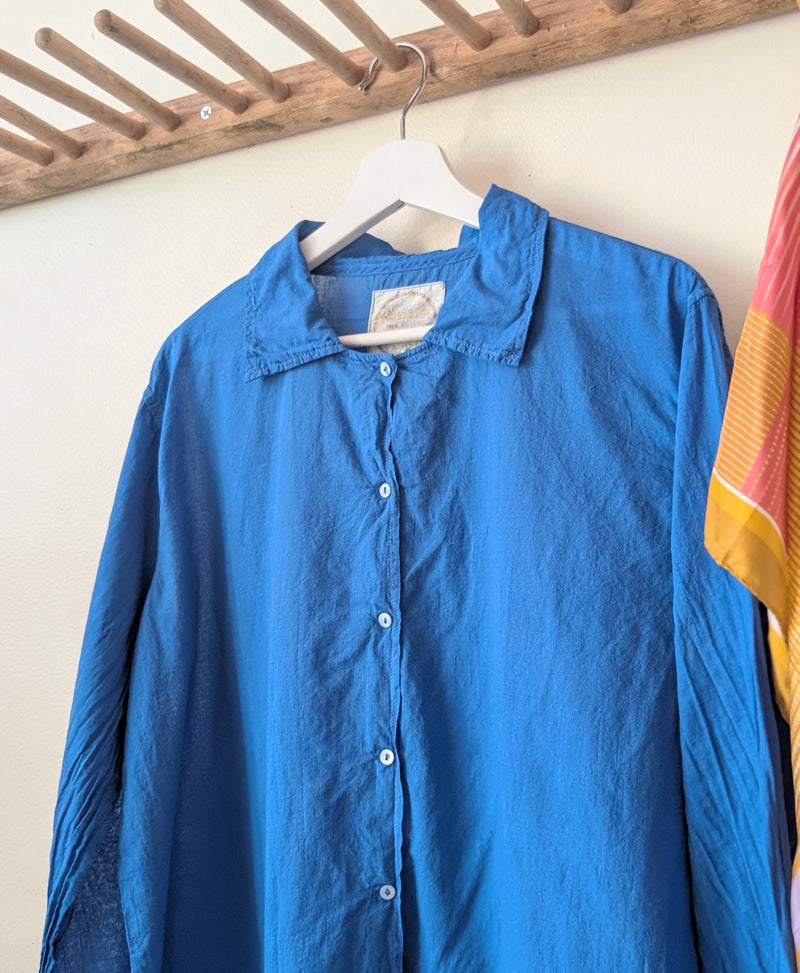 Blue shirt on a hanger against a white wall with a colorful towel in the background.

Auntie Oti button down khaki lightweight cotton shirt sowa boston small business gift shop boutique