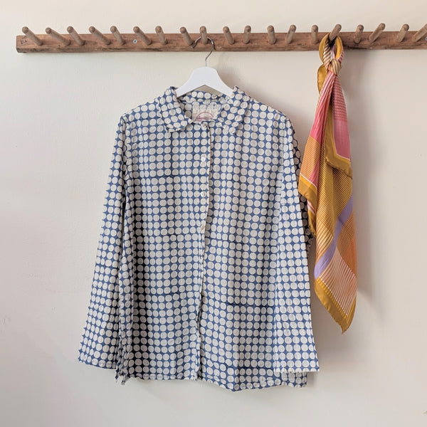 Blue patterned shirt and colorful scarf hanging on a wooden rack against a plain wall.

Auntie Oti button down cotton shirt polka dot block printed sowa boston small business gift shop boutique
