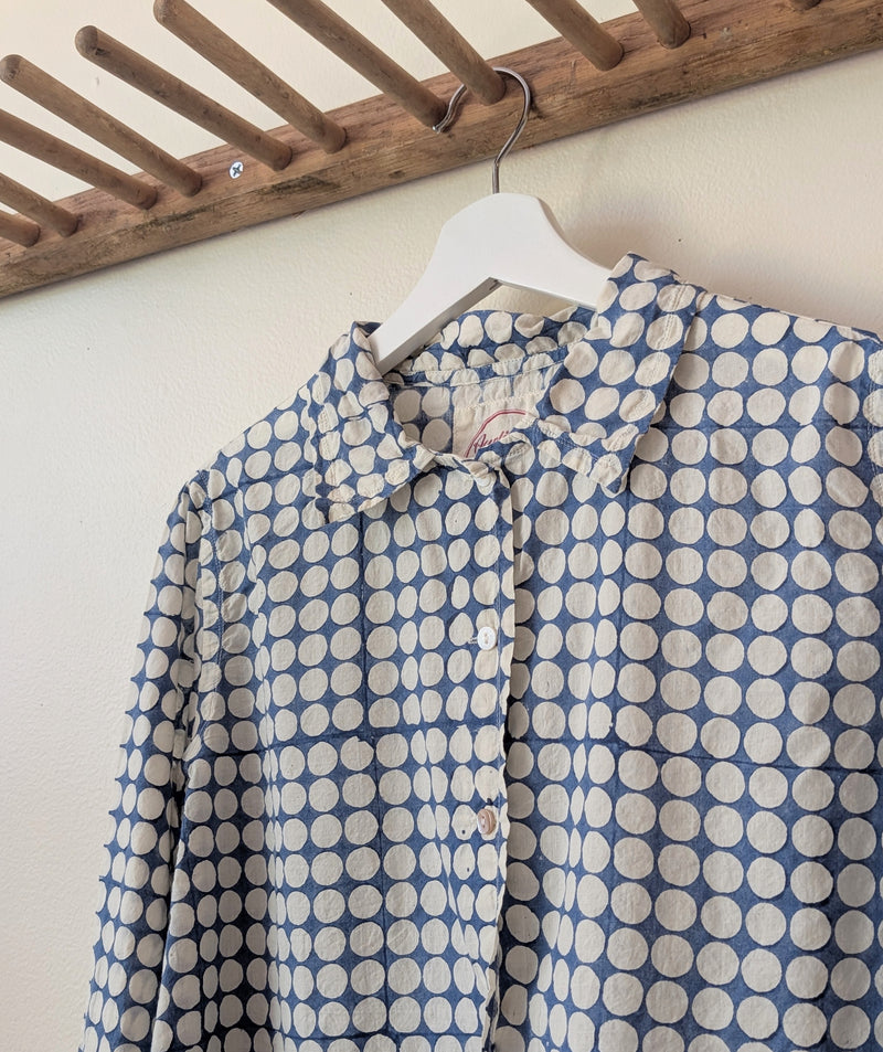 Blue and white polka dot shirt on a hanger against a wooden rack.

Auntie Oti button down cotton shirt polka dot block printed sowa boston small business gift shop boutique