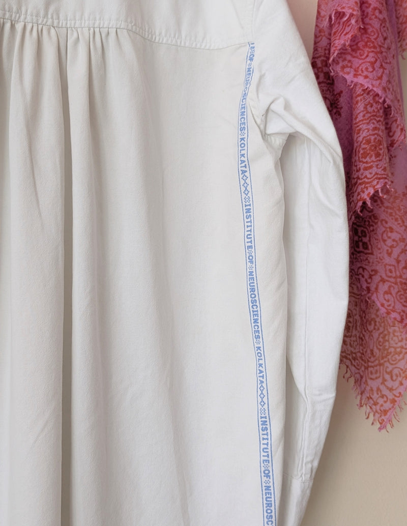 Close-up of a white shirt with text on the collar and a pink patterned fabric in the background.

Auntie Oti button down cotton oversized upcycled shirt sowa boston small business gift shop boutique