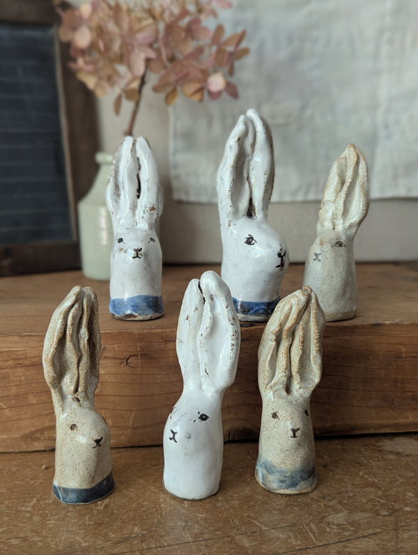 Set of ceramic rabbit figurines on a wooden surface with a blurred floral arrangement in the background.

Handmade and hand-painted rabbit head sculptures figurines by Charlotte salt small business sowa Boston gift shop boutique store