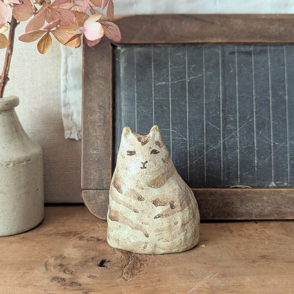 Ceramic cat figurine on a wooden surface with a chalkboard and vase in the background

Pinched Fat Cat ceramic sculpture by Charlotte Salt sowa Boston small business gift shop boutique store