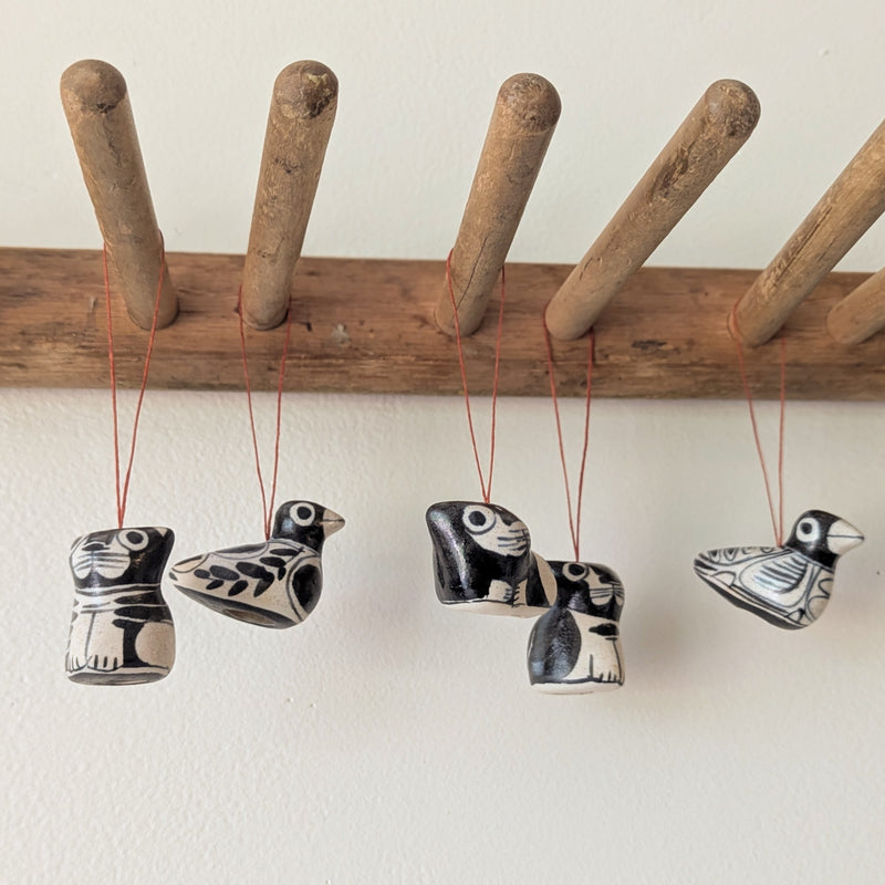 Set of five black and white ceramic bird figurines hanging from a wooden rod against a white wall.

Anna Hepler clar ceramic bird ornaments holiday figurines handmade hand painted New England Boston Massachusetts sowa gift shop store boutique