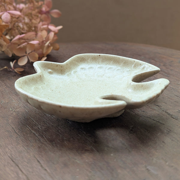 Ceramic bird-shaped dish on a wooden surface with dried flowers in the background