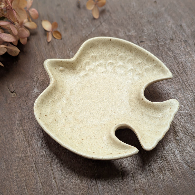 Ceramic bird-shaped dish on a wooden surface with dried flowers.