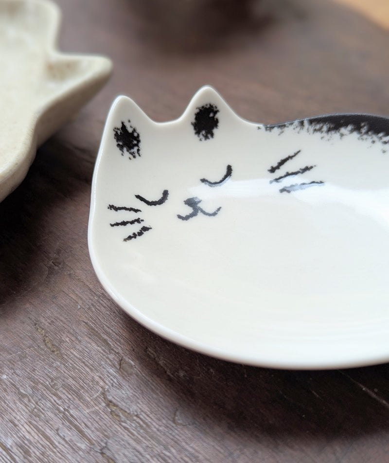 White ceramic dish shaped like a cat face on a wooden surface