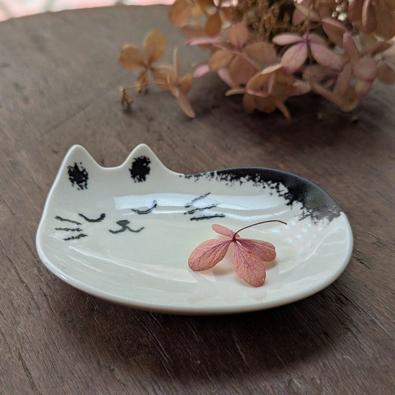 Cat-shaped ceramic dish with a pink dried flower on a wooden surface