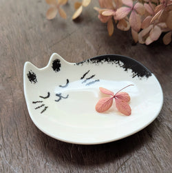 Cat-shaped ceramic dish with a pink leaf on a wooden surface