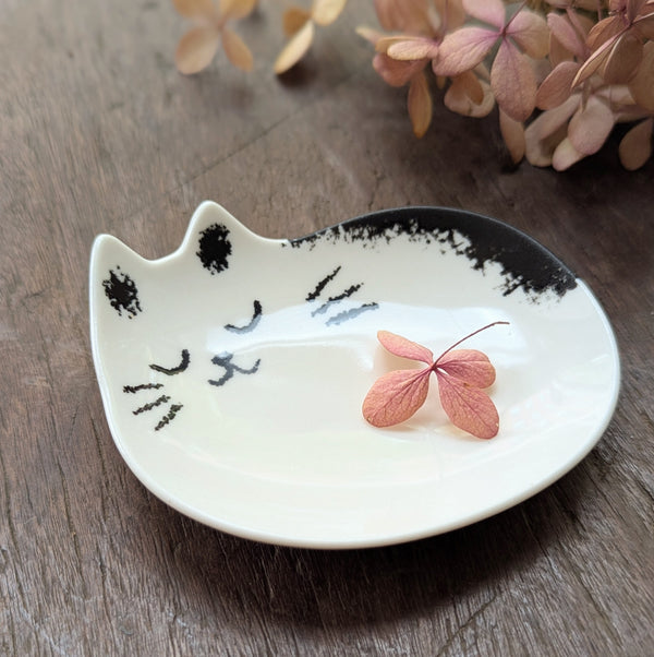 Cat-shaped ceramic dish with a pink leaf on a wooden surface
