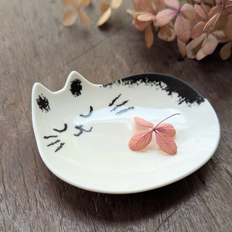Cat-shaped ceramic dish with a pink leaf on a wooden surface