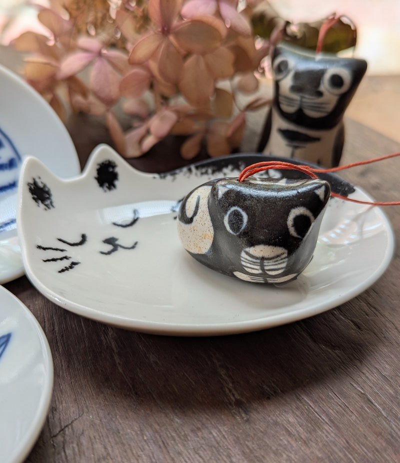 Ceramic cat-shaped dish with a small cat figurine on a wooden surface.