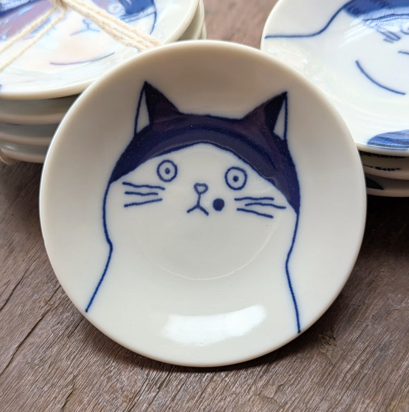 Small ceramic dish with a blue cat illustration on a wooden surface