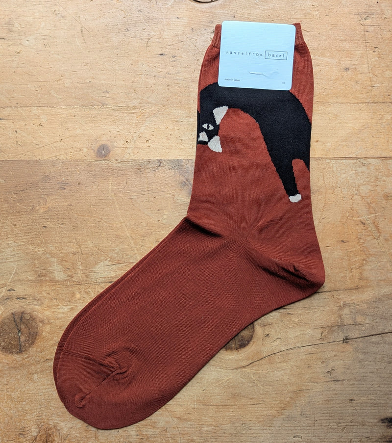 Brown sock with black cat design on a wooden surface