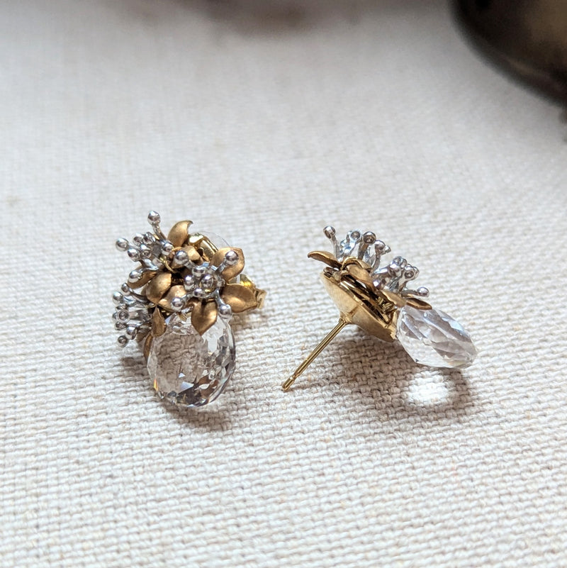 Pair of brass and crystal glass earrings on a textured surface.