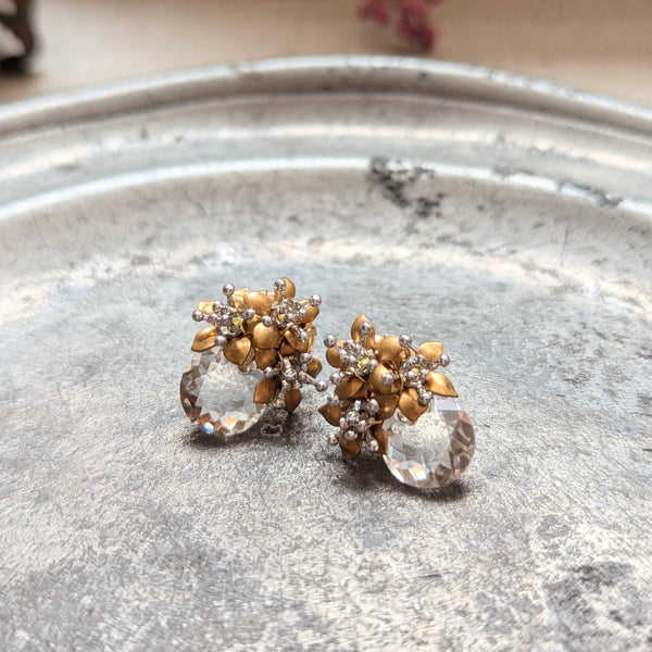 Pair of brass and crystal glass earrings on a textured surface.
