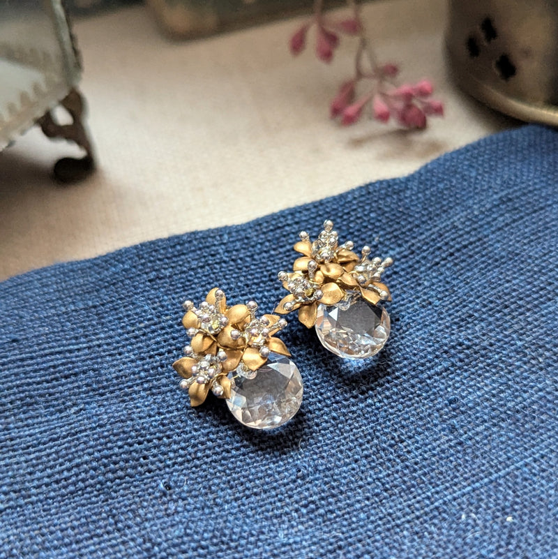 Pair of brass and crystal glass earrings on a textured surface.