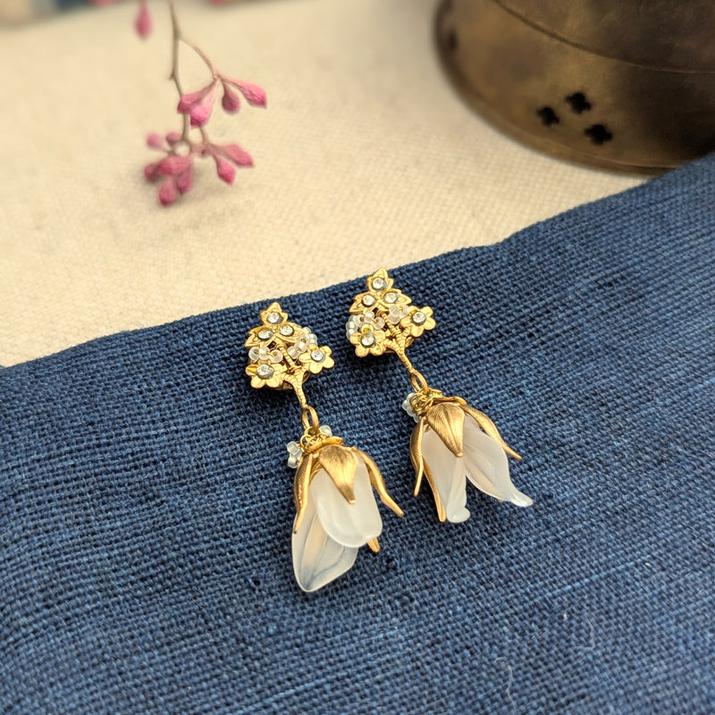 Brass, crystal, and lucite dangle earrings inspired by sweet pea blossoms on a textured background
