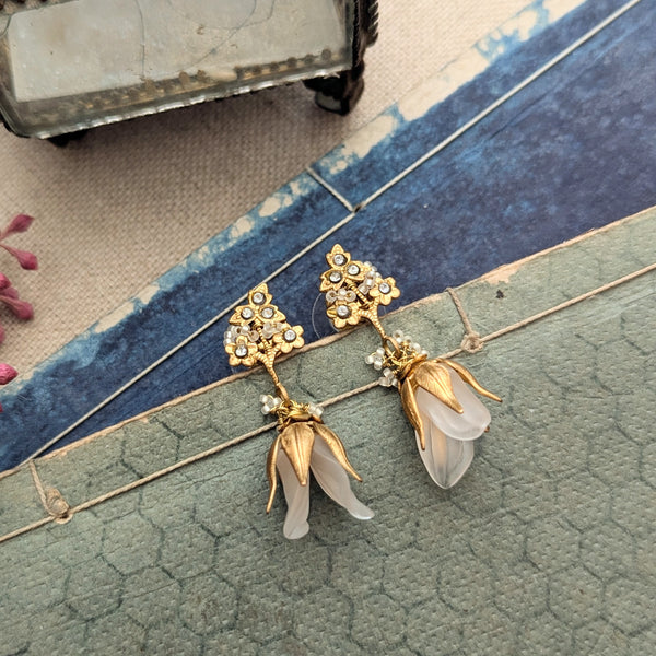 Brass, crystal, and lucite dangle earrings inspired by sweet pea blossoms on a textured background