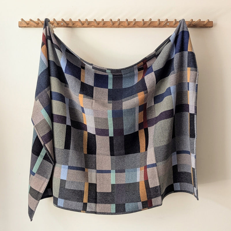 Blue and Gray plaid blanket hanging on a wooden rack against a white background