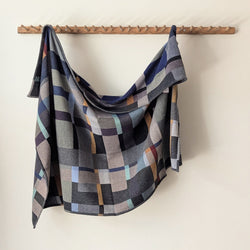 Blue and Gray plaid blanket hanging on a wooden rack against a white background