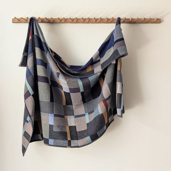 Blue and Gray plaid blanket hanging on a wooden rack against a white background