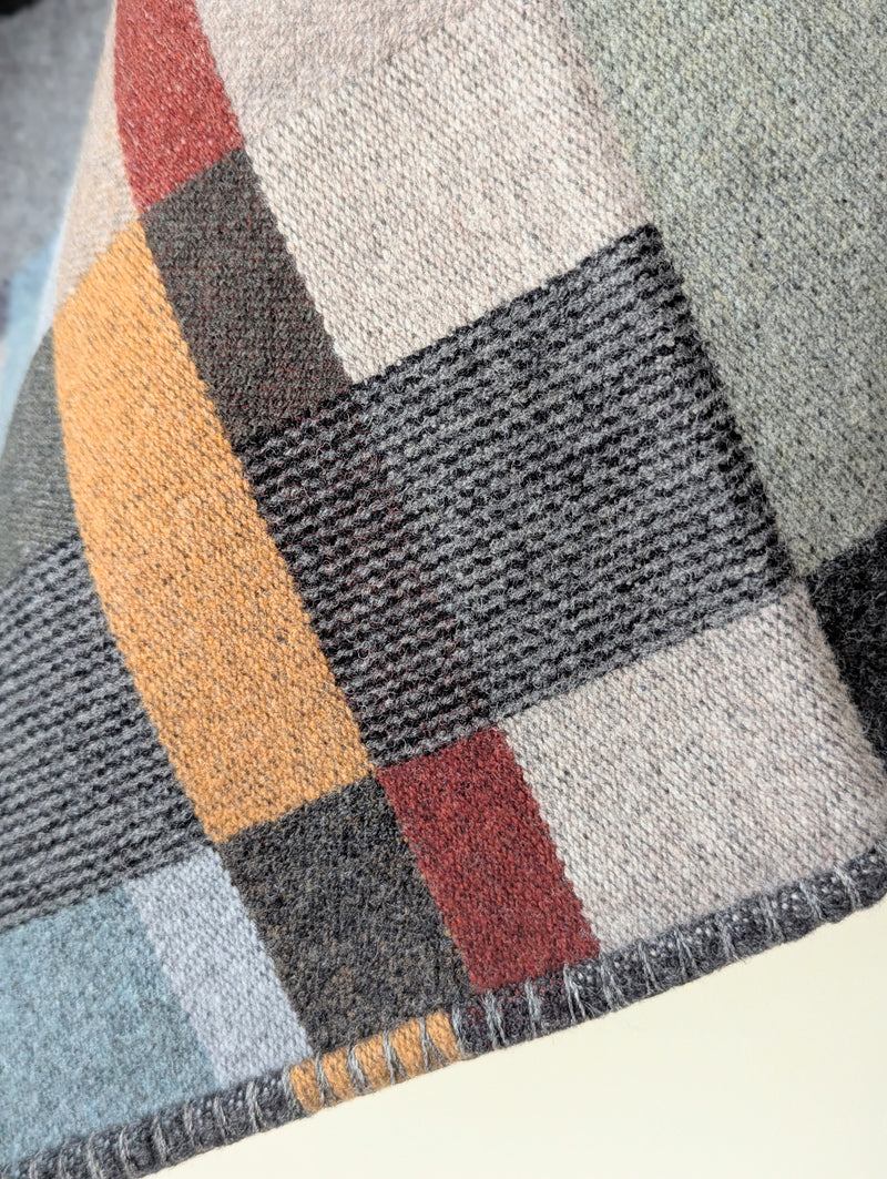 Blue and Gray plaid blanket hanging against a white background