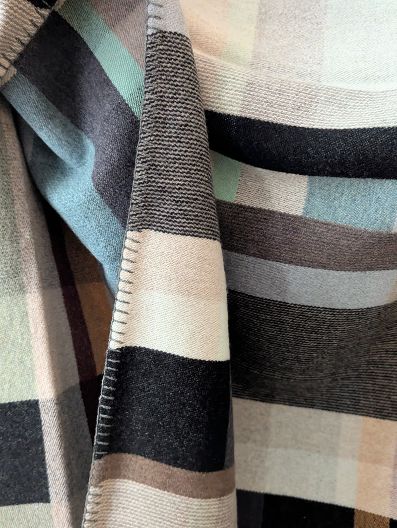 Multicolored blanket hanging against a white background.