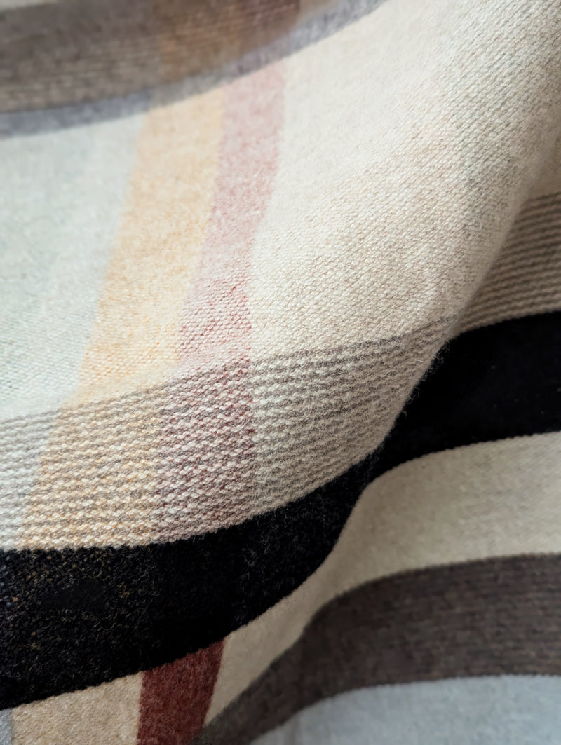 Multicolored blanket hanging against a white background.