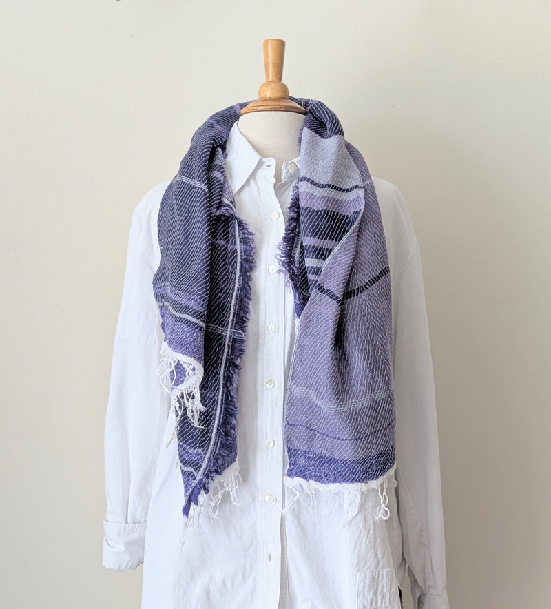 Mannequin wearing a white shirt with a purple and blue patterned scarf draped over it against a plain background
