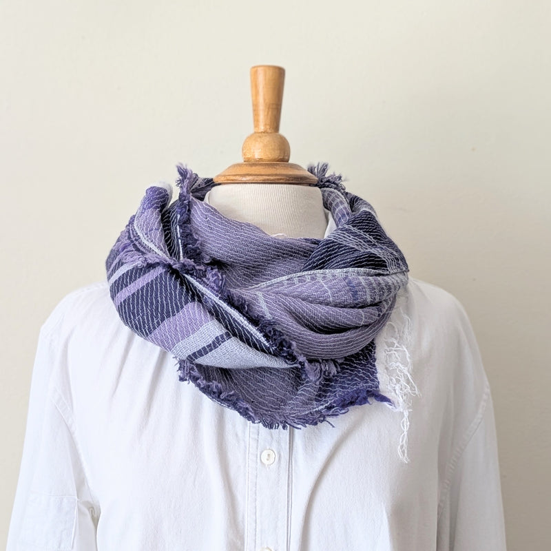 Mannequin wearing a white shirt with a purple scarf draped over it against a plain background