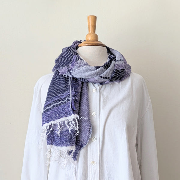 Mannequin wearing a white shirt with a purple scarf draped over it against a plain background