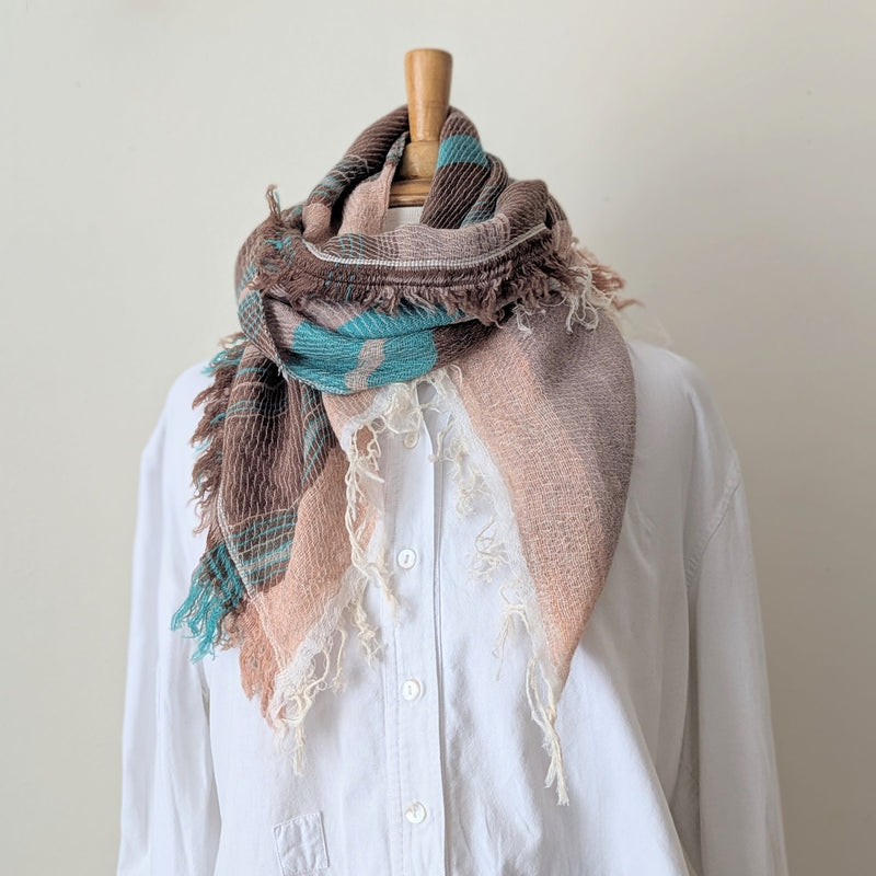 Brown and turquoise scarf draped over a white shirt on a mannequin against a plain background
