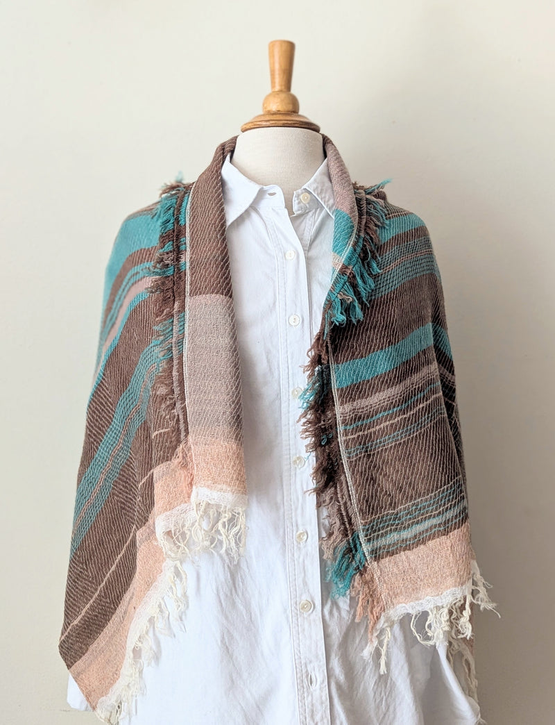 Mannequin wearing a white shirt with a striped brown and blue shawl draped over it against a plain background