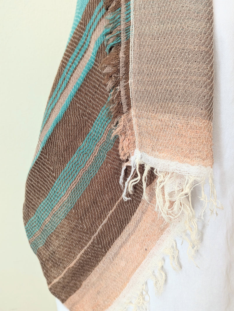 Knit scarf with brown, turquoise, and beige stripes on a light background