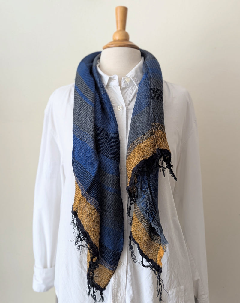 Mannequin wearing a blue and yellow stripe  scarf with a white shirt on a plain background