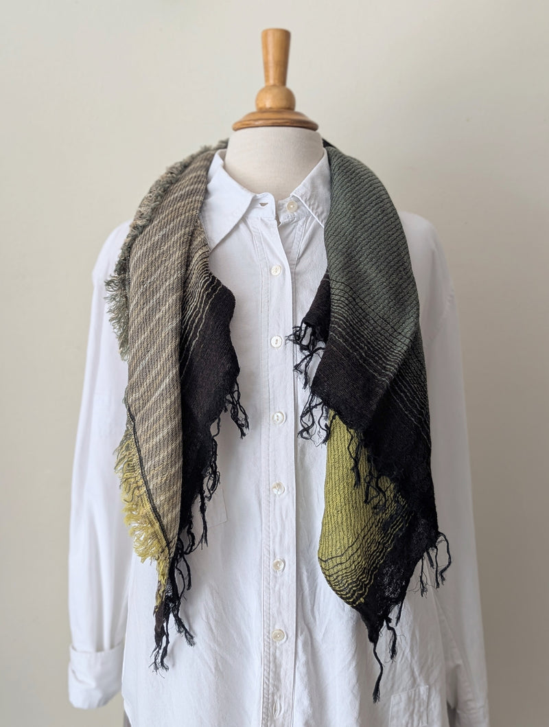 Mannequin wearing a white shirt with a black and green patterned scarf draped over it.