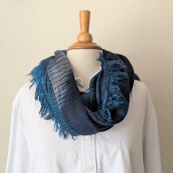 Navy and teal scarf on a mannequin wearing a white shirt against a white background
