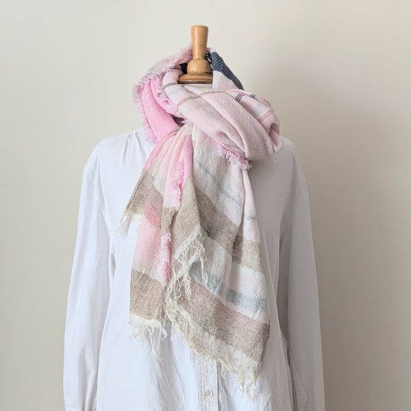 Mannequin wearing a white shirt with a pink and beige scarf draped over it against a plain background