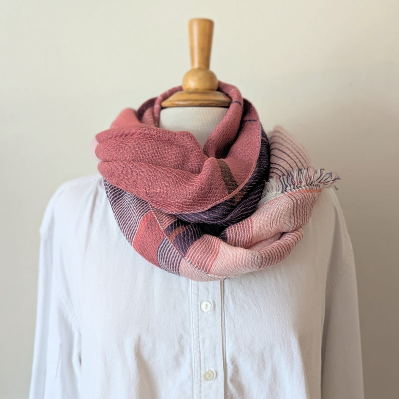 White shirt with a pink and blue striped scarf draped over it on a mannequin against a white background