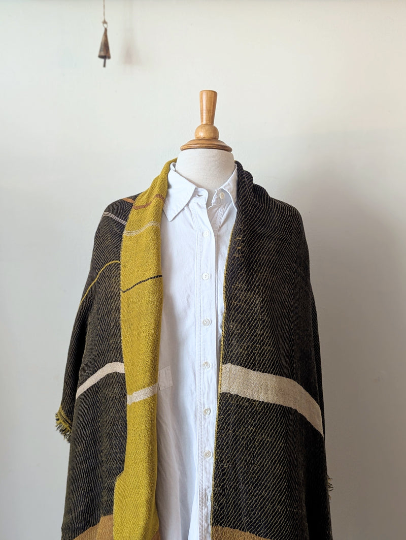Mannequin wearing a plaid scarf with yellow, black, and brown colors on a white background.