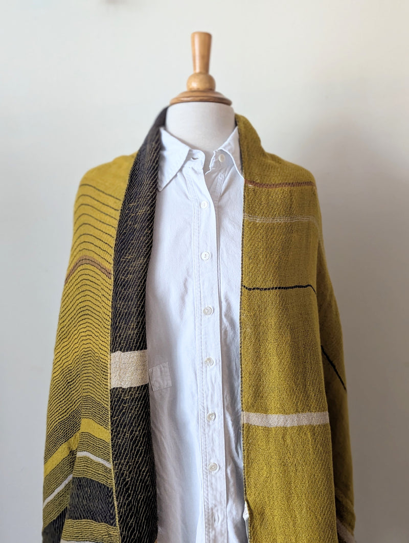 Mannequin wearing a plaid scarf with yellow, black, and brown colors on a white background.