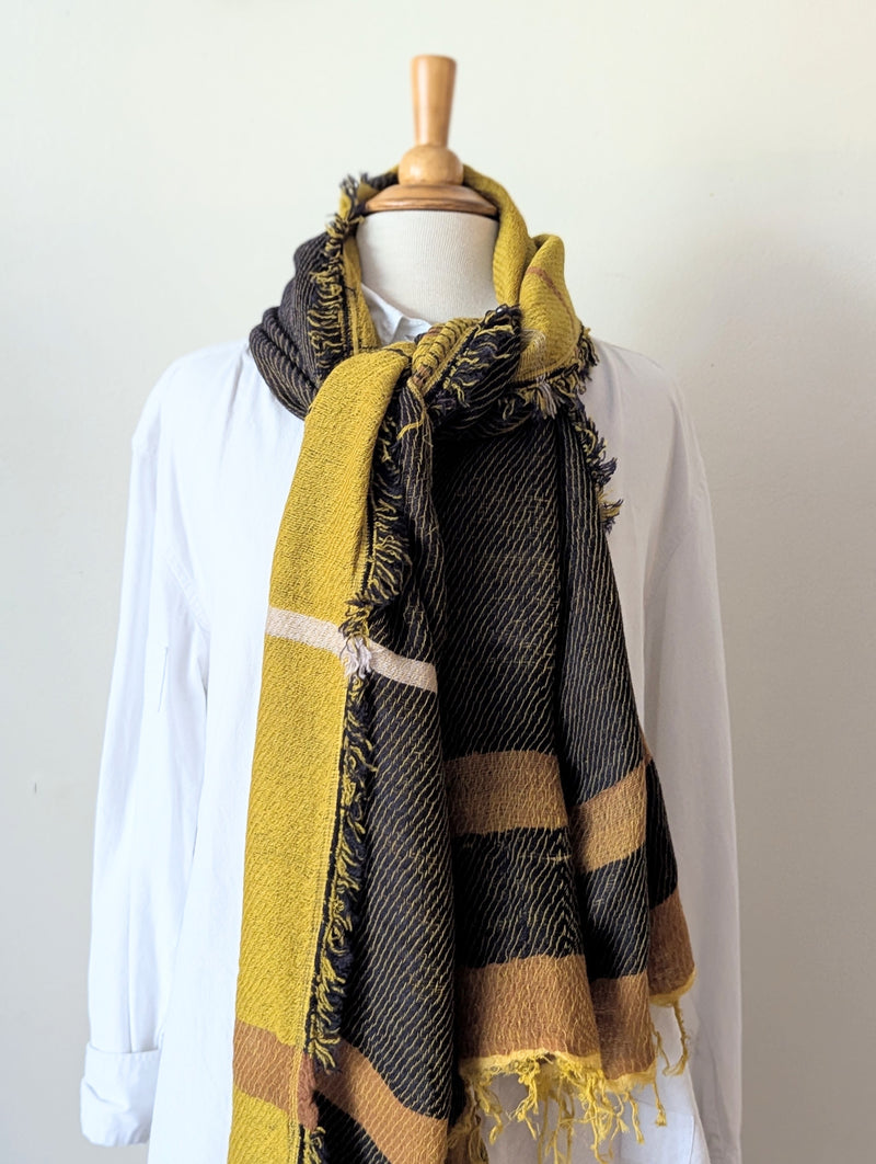Mannequin wearing a plaid scarf with yellow, black, and brown colors on a white background.