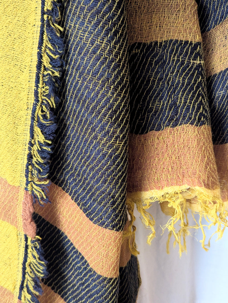 Striped ochre and black scarf hanging against a white wall