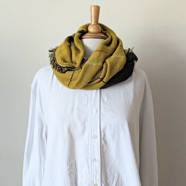 Yellow plaid scarf draped over a white shirt on a mannequin against a plain background