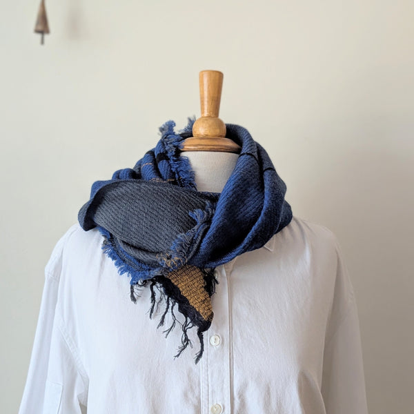 Blue knitted scarf on a mannequin with a white shirt against a plain background