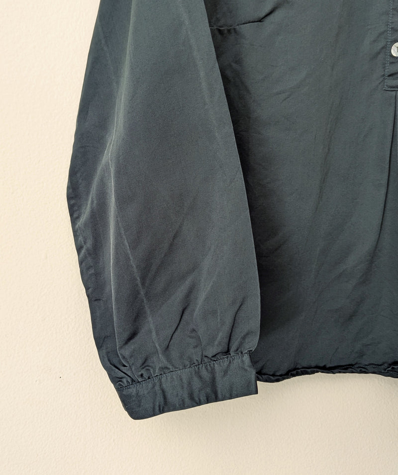 Dark green blouse sleeve and chest area on a beige background