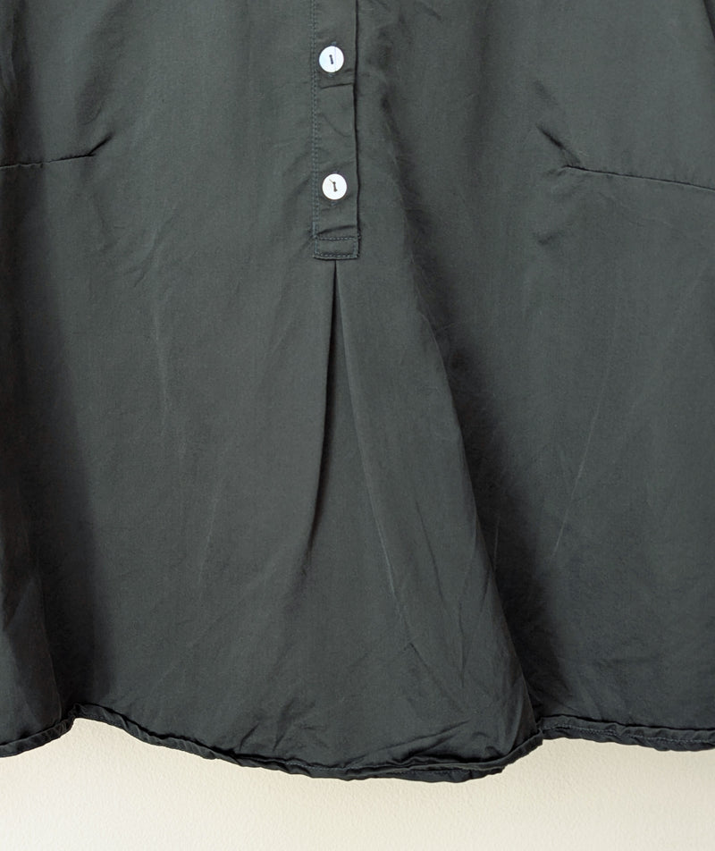 Close-up of a dark green blouse rt on a beige background