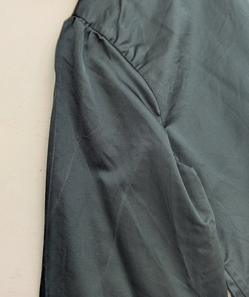 Sleeve of a dark green blouse on a beige background