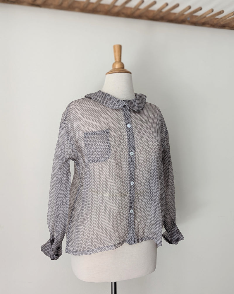 Sheer gray blouse on a mannequin against a white background